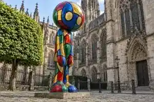 Stained glass style cartoon abstract character sculpture in a Cologne cathedral close
