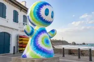 Three-quarter view of a 2.4 m cartoon abstract character covered in concentric tie-dye rings
