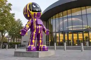 Cartoon astronaut sculpture covered in frozen paint drips on a planetarium forecourt in Leiden