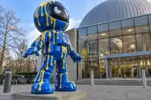 Three-quarter view of a 2.4 m astronaut sculpture with raised glossy vertical paint runs