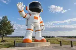 Detail of the oversized visor band and safety-orange patches on a giant cartoon astronaut