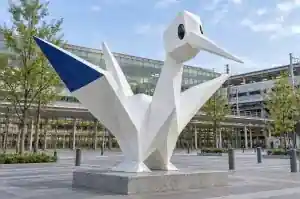 Three-quarter view of a 2.2 m cast origami crane sculpture with sharp folded facets