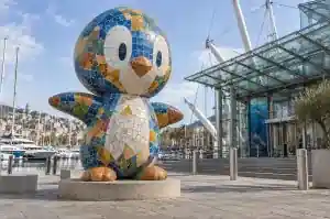 Mosaic-tiled cartoon penguin sculpture on an aquarium plaza in Genoa