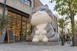Detail of the rounded head and fat seam of an inflated vinyl-look cartoon cat sculpture