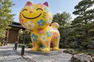 Three-quarter view of a 2.1 m cartoon cat sculpture covered in multicolour daisy flowers