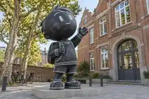 Chalkboard-finished cartoon child sculpture standing at a primary school entrance in Ghent