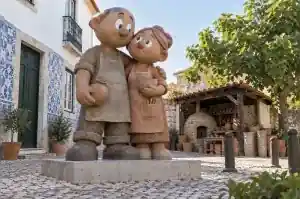 Three-quarter view of a 1.9 m cartoon couple sculpture with matte hand-pressed clay texture