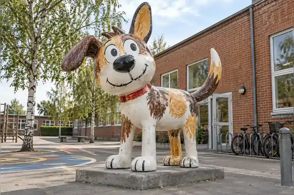 Cartoon dog sculpture finished to look like a child's crayon drawing in a Copenhagen schoolyard