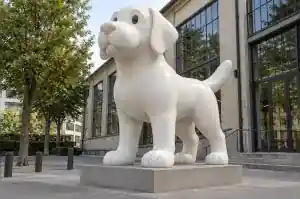 Three-quarter view of a 2.4 m single-colour cartoon labrador sculpture beside a gallery entrance
