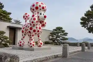 Polka-dot cartoon poodle sculpture in fibreglass in a garden on Naoshima art island