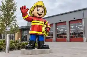 Detail of the cartoon firefighter's helmet and black contour lines against the station behind