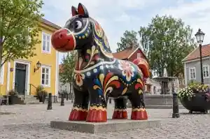 Folk painted cartoon horse sculpture in a Swedish town square with red and gold scrollwork