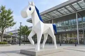 Three-quarter view of a 2.5 m paper-folded cartoon horse sculpture in paper-white with an indigo accent