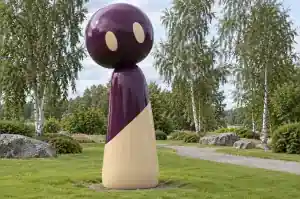Detail of the oversized rounded head of a cartoon abstract character sculpture in aubergine and sand